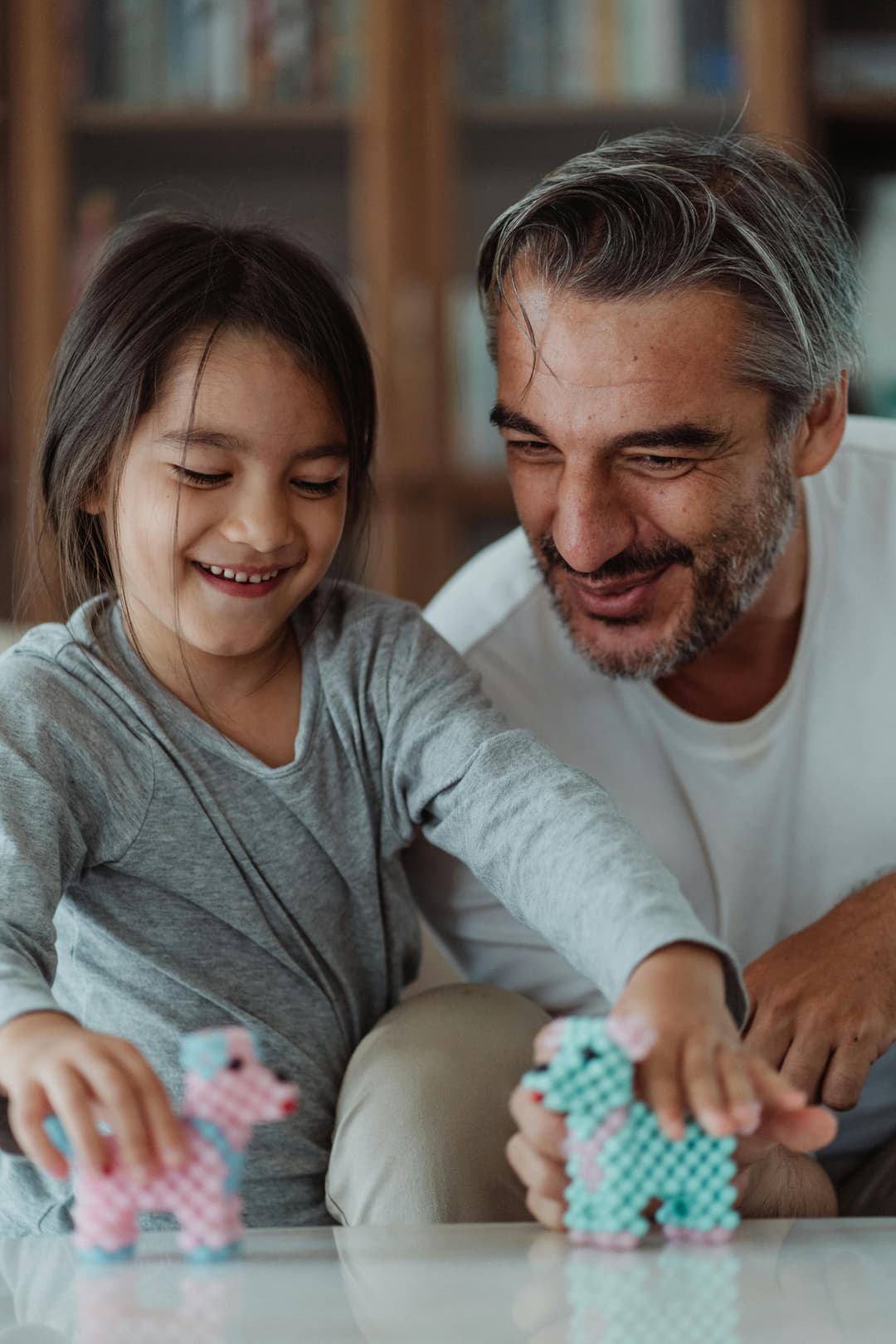 Mama und Tochter teilen einen lachenden Moment beim Spielen — echte Momente, keine Inszenierung
